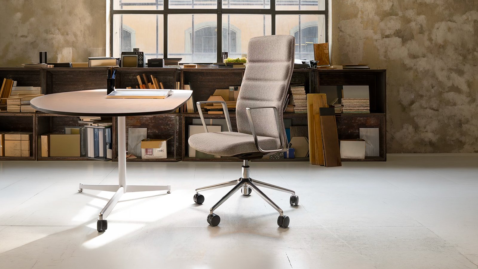 Sillón That’s it Executive de Quinti con brazos fijos de aluminio junto a una mesa de despacho