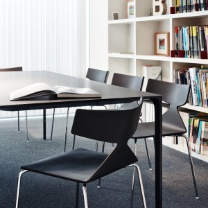 Silla Saya de Arper junto a una mesa de madera maciza